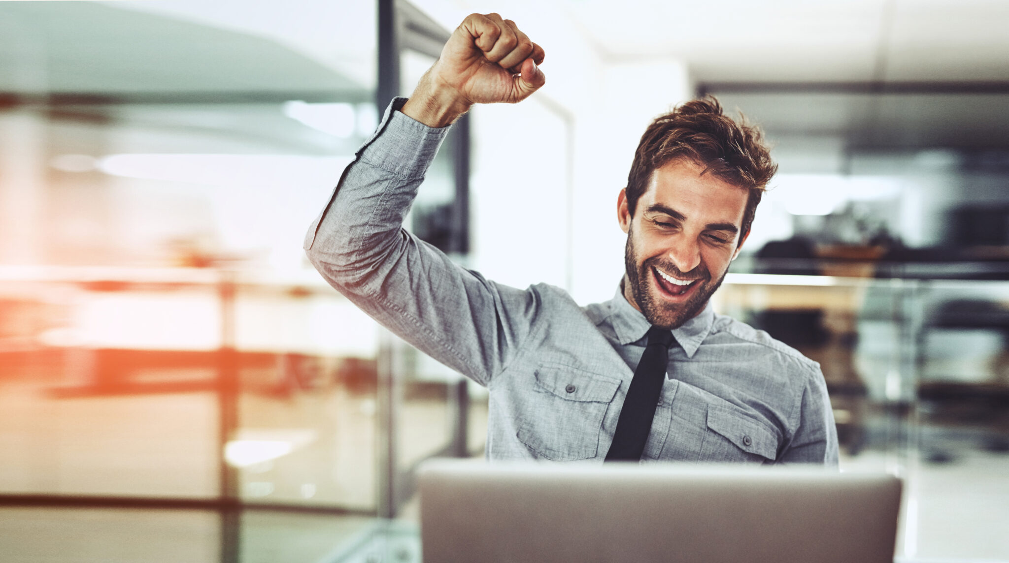 Shot of a handsome young businessman doing a fist pump while working on a laptop in an office